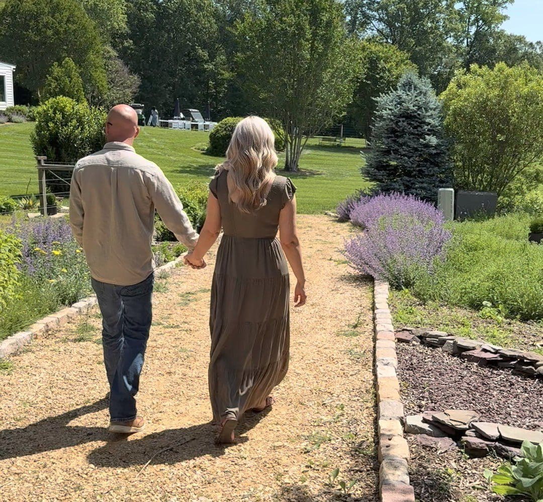 Couple walking on garden path holding hands.