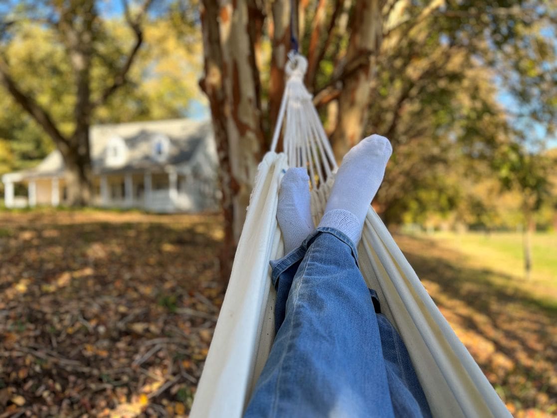 Relaxing in hammock with distant house view.